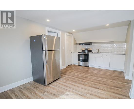 A kitchen with a stainless steel refrigerator and wooden flooring.