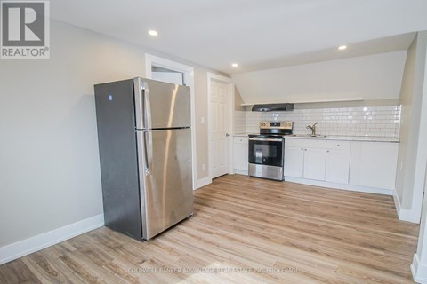 A kitchen with a stainless steel refrigerator and wooden flooring.