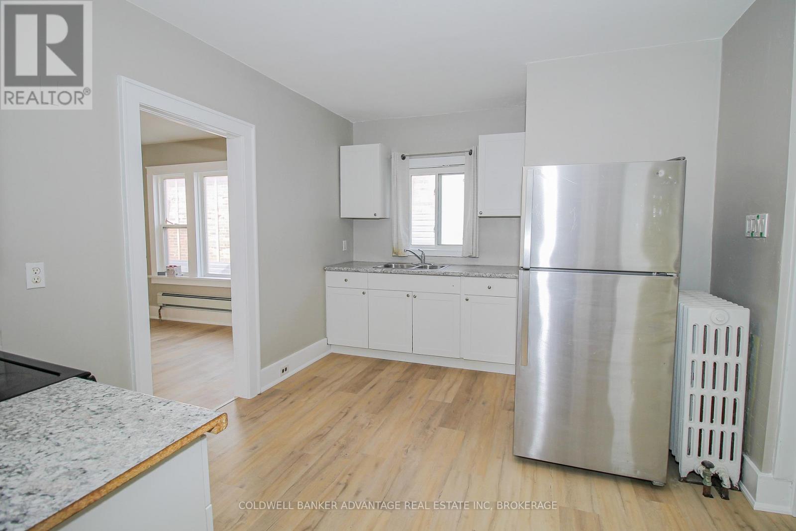 A kitchen with white cabinets and a stainless steel refrigerator.