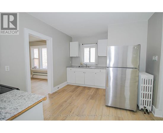 A kitchen with white cabinets and a stainless steel refrigerator.