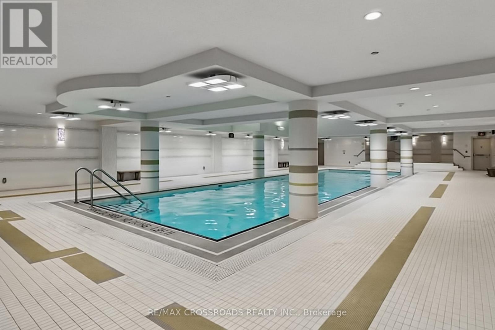 A large indoor swimming pool with a tiled floor and walls.