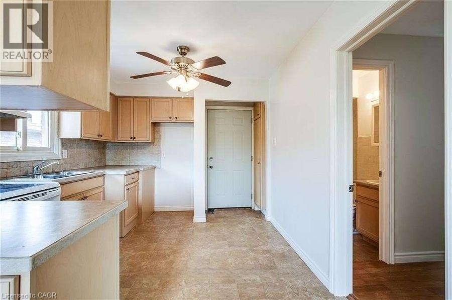 A kitchen with a fan on the ceiling and a door to the hallway.