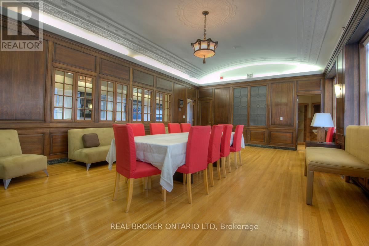 A dining room with a long table set for six with red chairs.