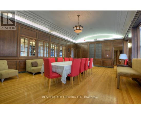 A dining room with a long table set for six with red chairs.