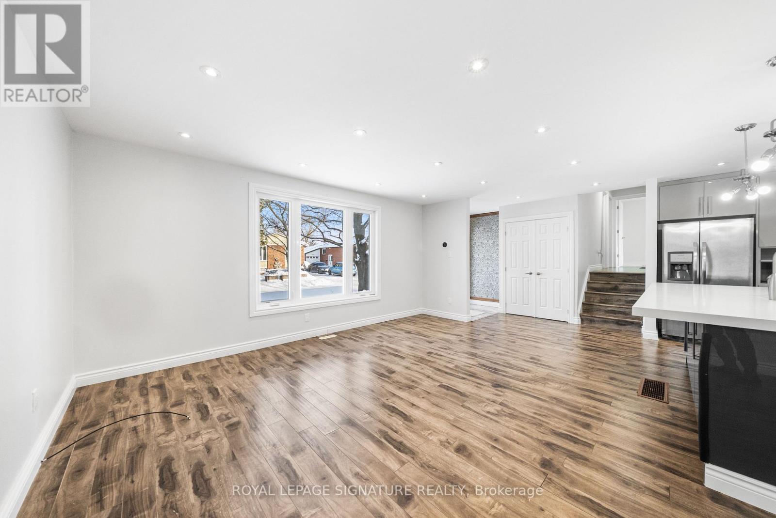 A spacious room with wooden flooring and white walls.