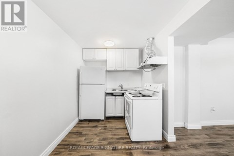 A white kitchen with a sink and a refrigerator.
