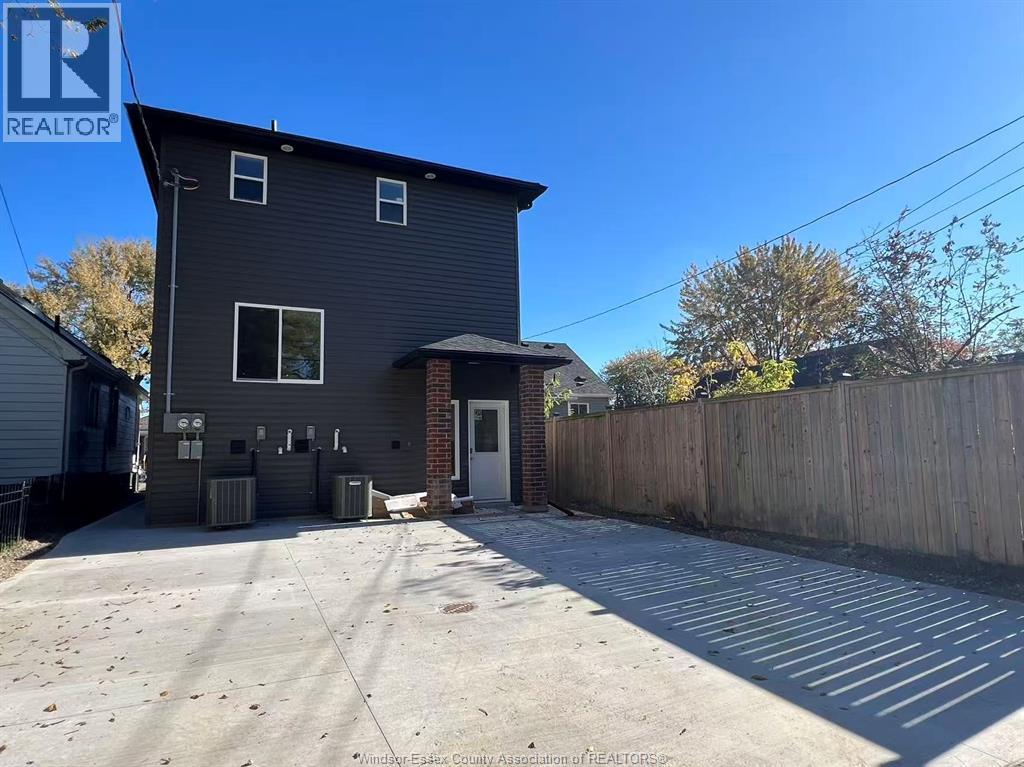 A grey house with a white door and windows is surrounded by a wooden fence.