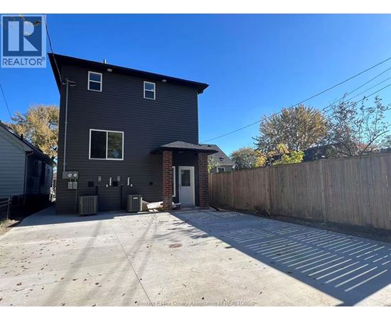 A grey house with a white door and windows is surrounded by a wooden fence.