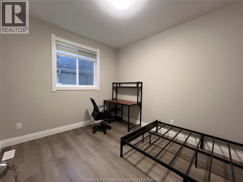 A bedroom with a bed frame and a desk with a chair.