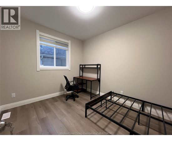 A bedroom with a bed frame and a desk with a chair.