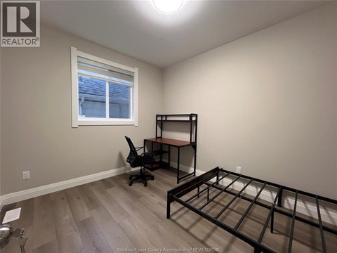 A bedroom with a bed frame and a desk with a chair.
