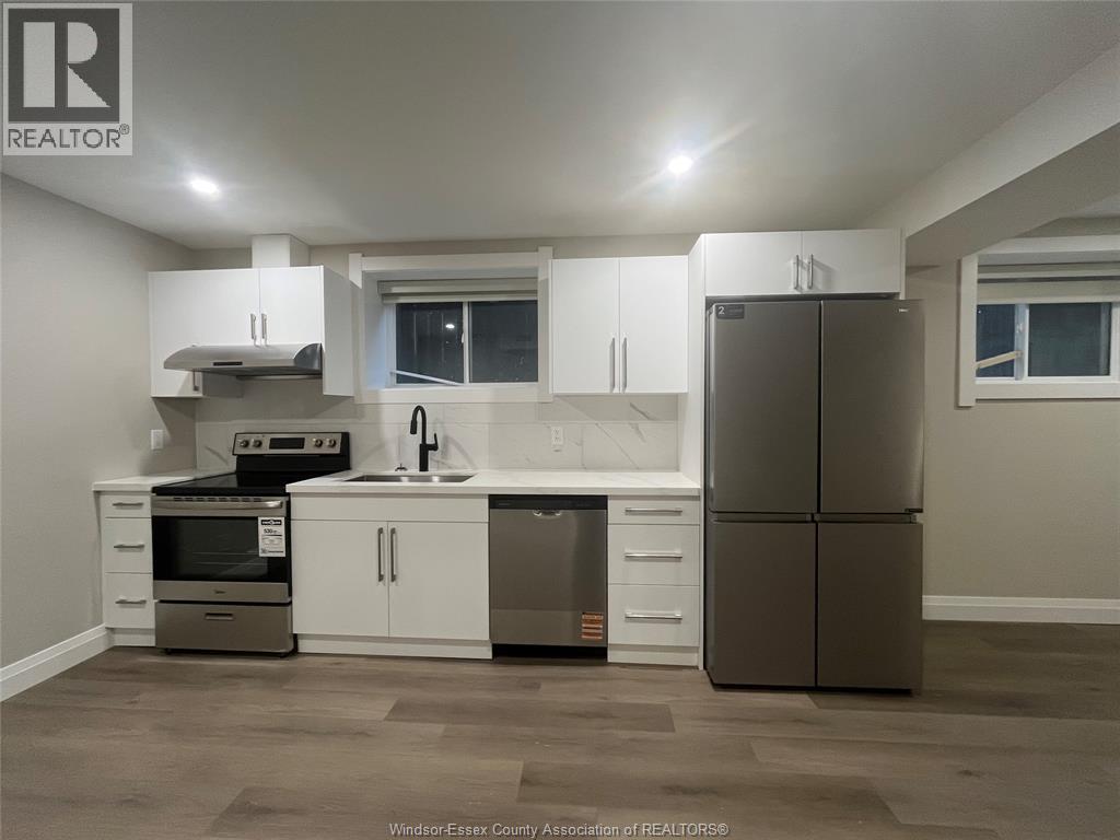A kitchen with a refrigerator, sink, and stove.