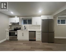 A kitchen with a refrigerator, sink, and stove.