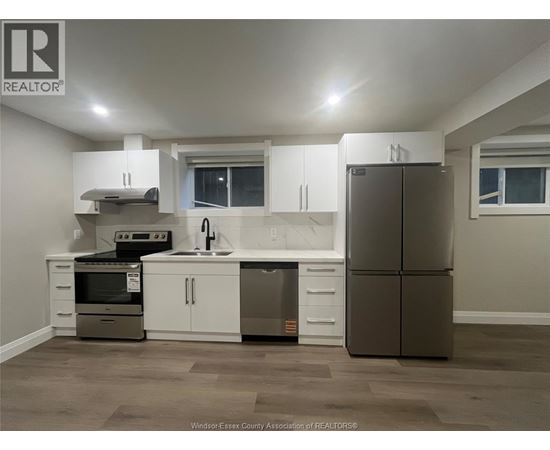A kitchen with a refrigerator, sink, and stove.