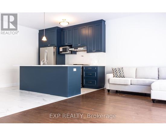 A kitchen with dark blue cabinets and a white couch.
