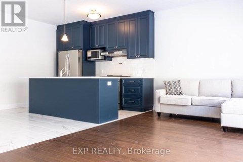 A kitchen with dark blue cabinets and a white couch.