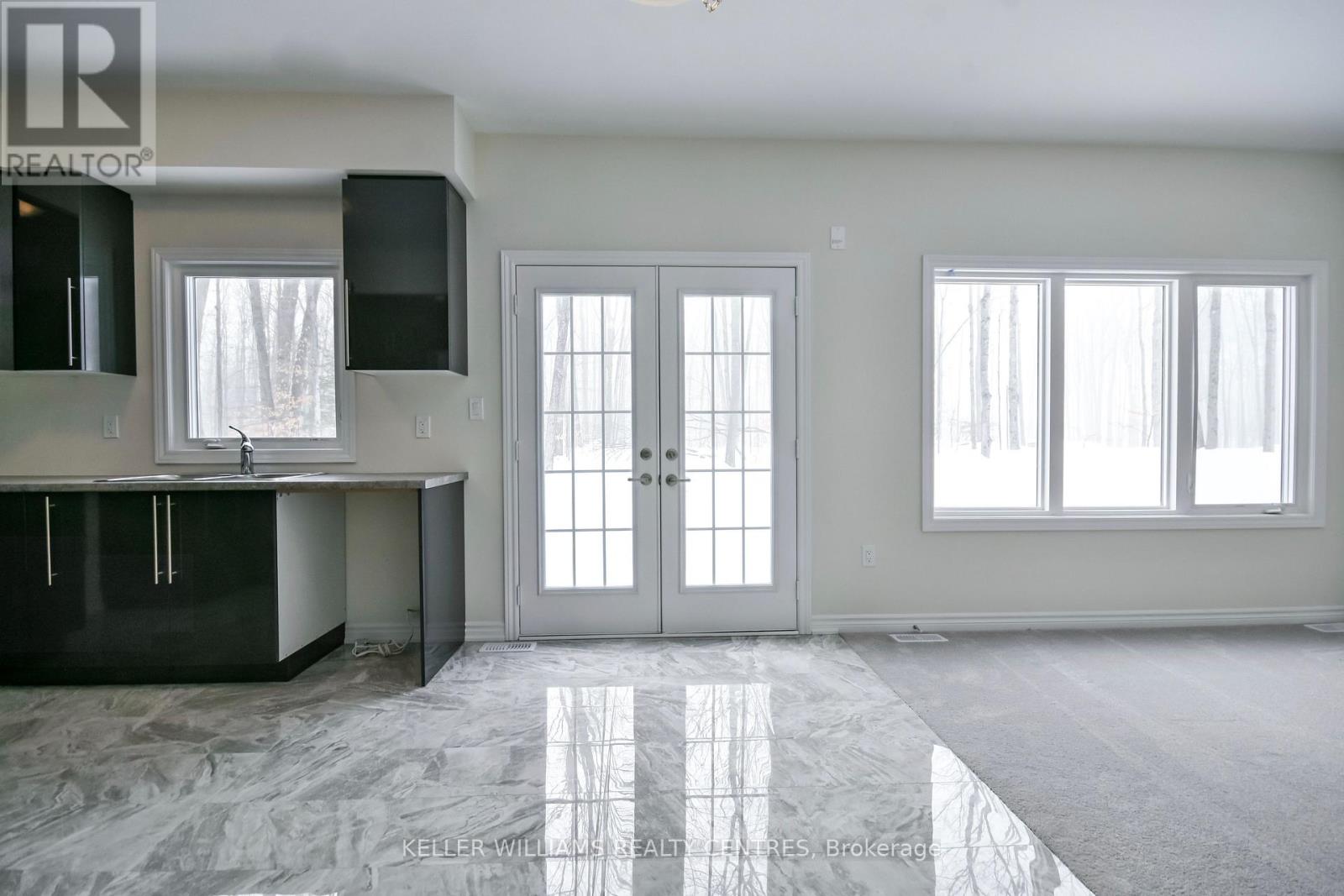 A spacious kitchen with black cabinets and a marble floor.