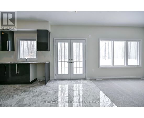 A spacious kitchen with black cabinets and a marble floor.