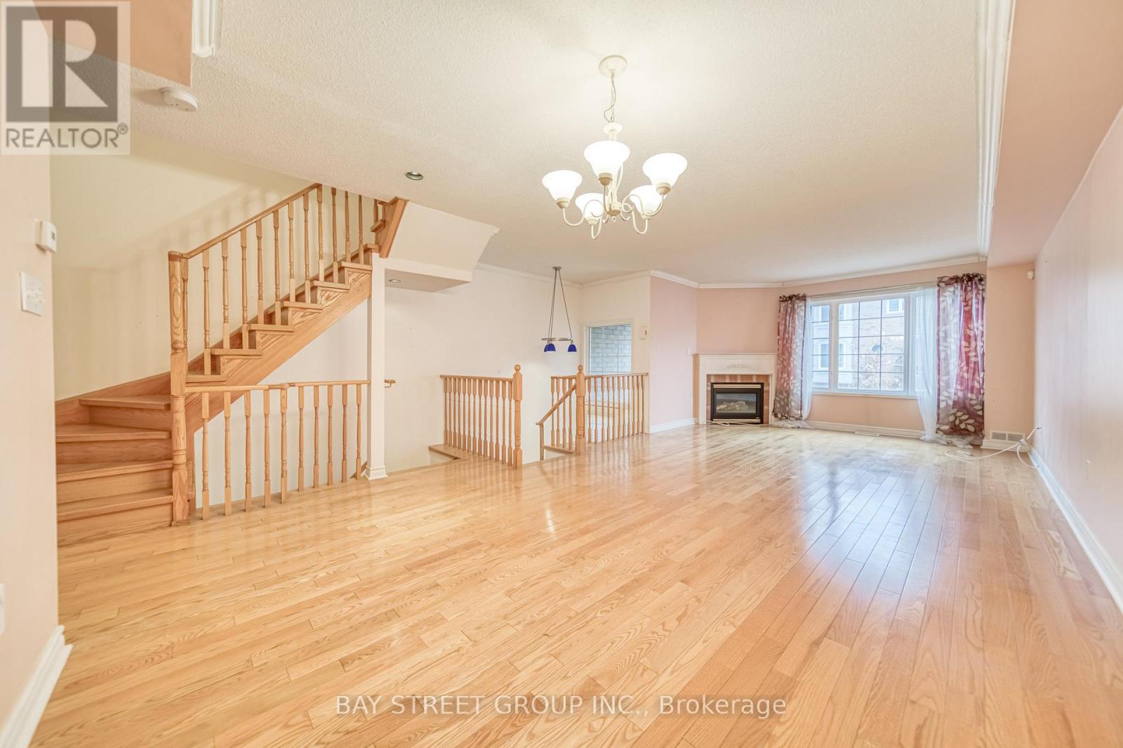 A spacious living room with a staircase and a chandelier.