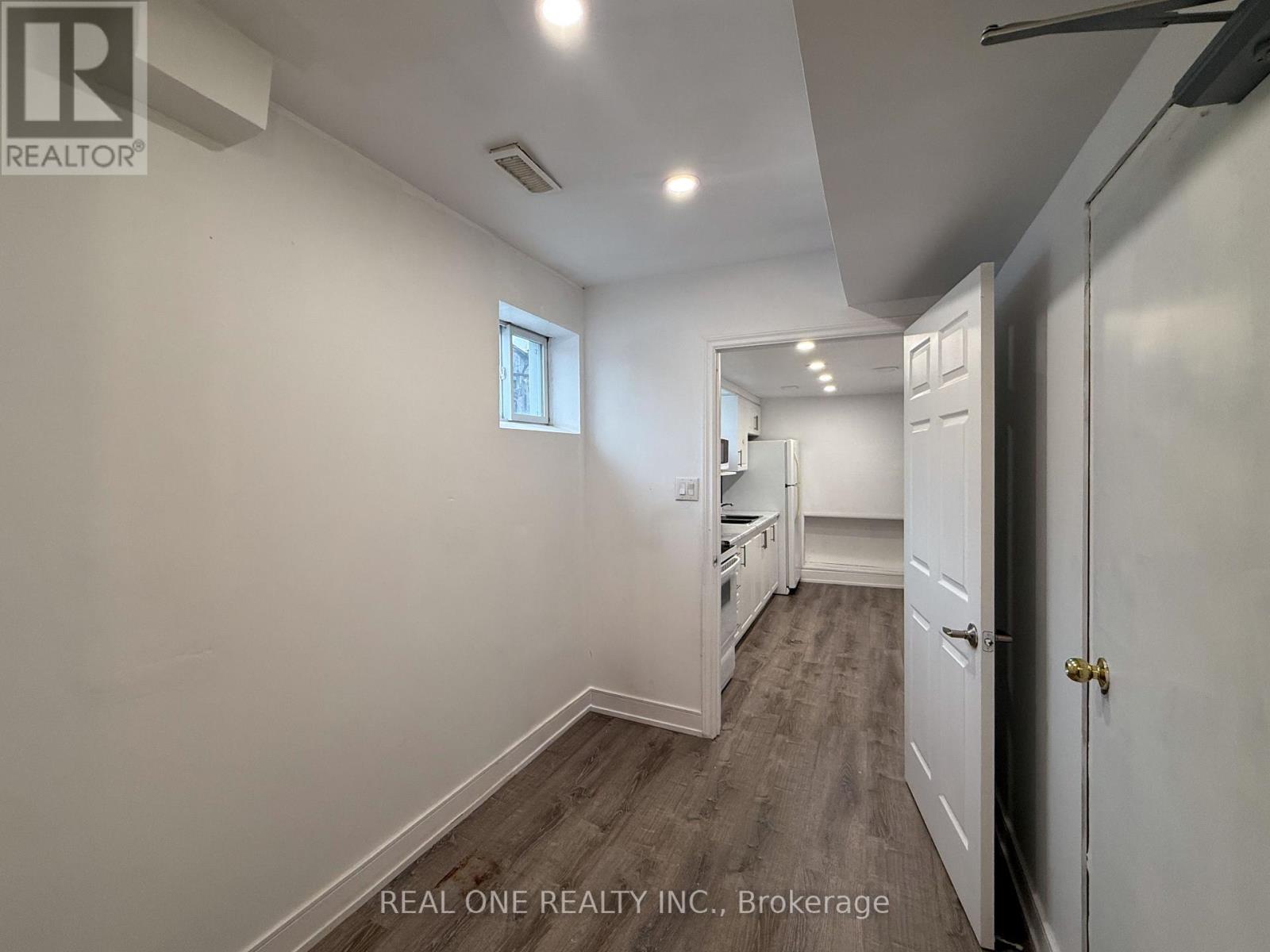 A white room with a window and a door leading to another room.