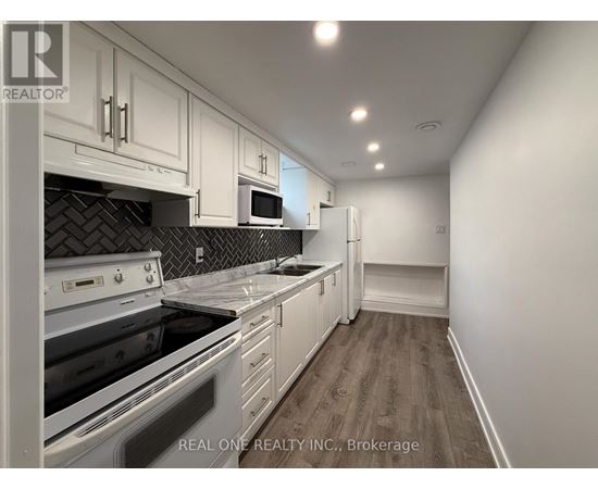 A kitchen with white cabinets and a black tile backsplash.
