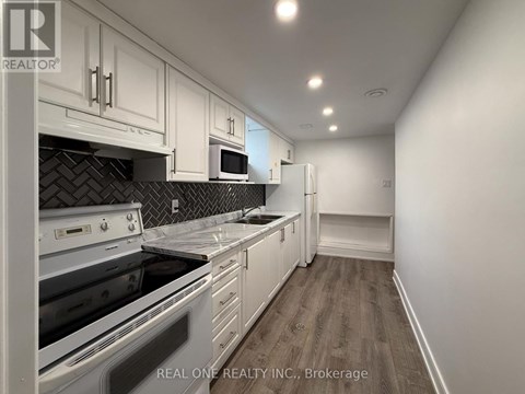 A kitchen with white cabinets and a black tile backsplash.