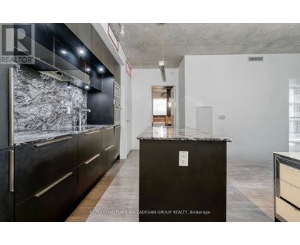 A kitchen with a black counter top and wooden floors.