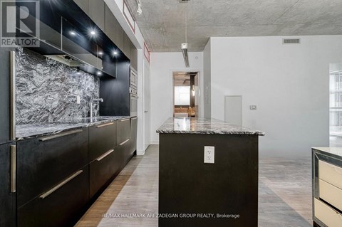 A kitchen with a black counter top and wooden floors.