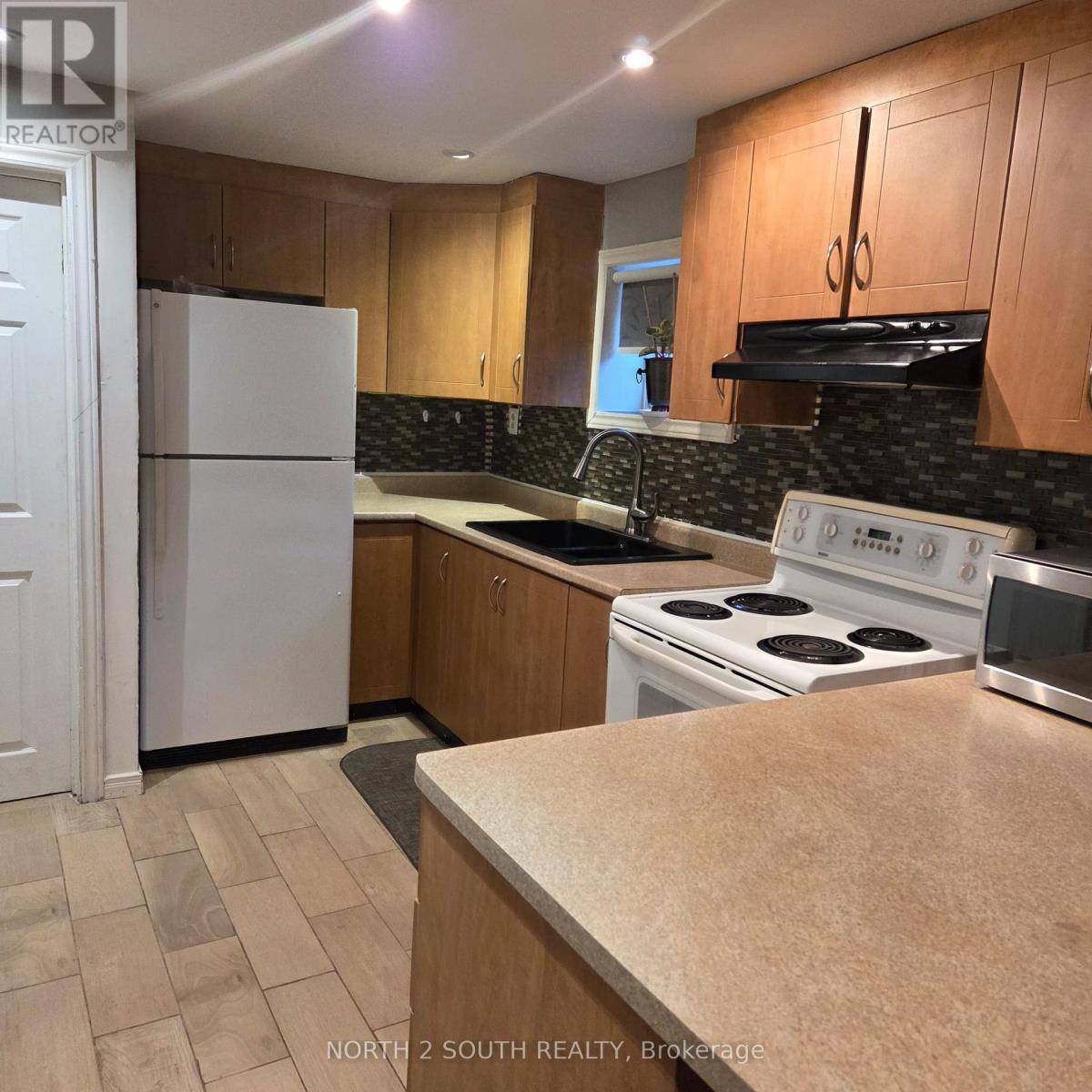 A kitchen with a white fridge and stove top oven.