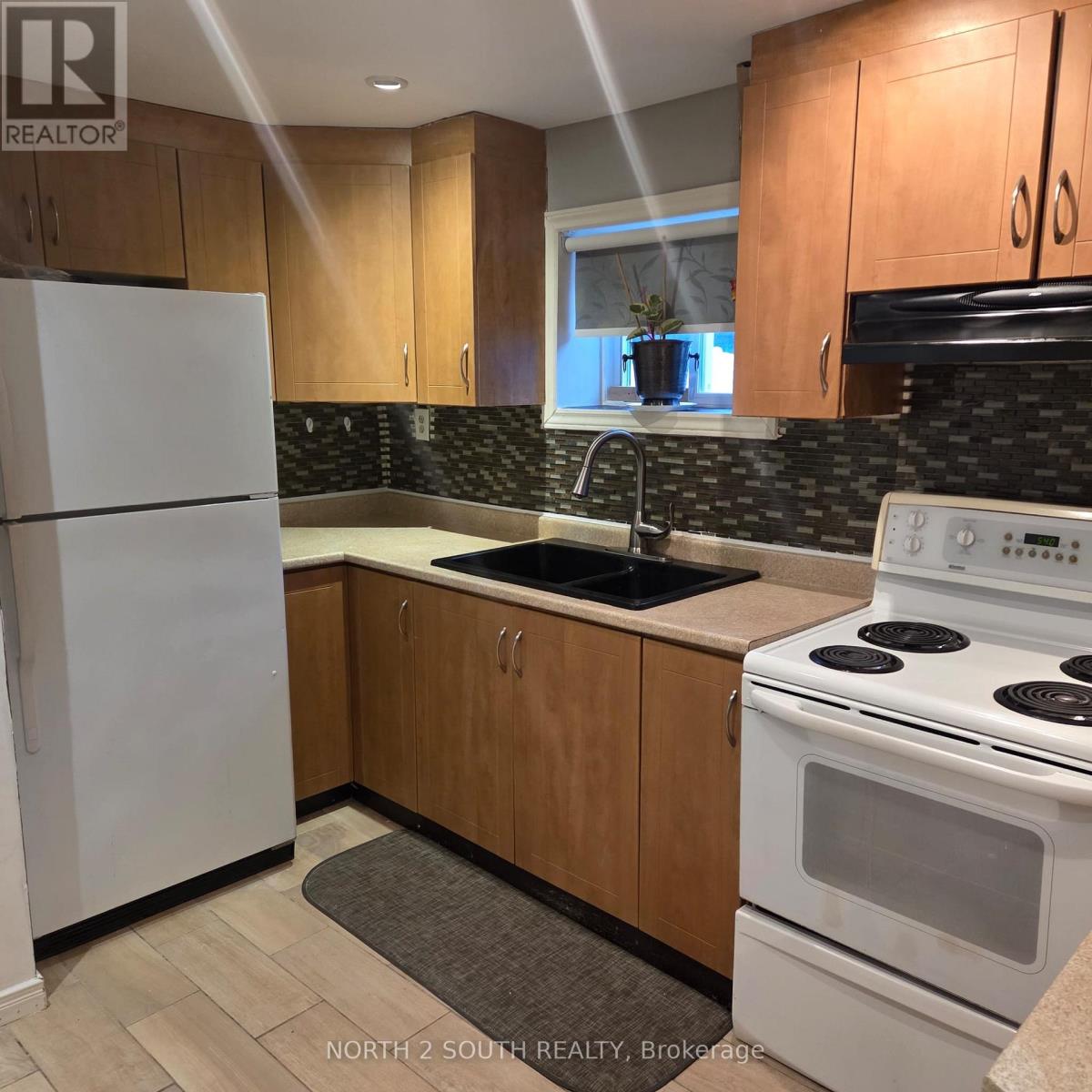 A kitchen with a white fridge, white stove, and wooden cabinets.