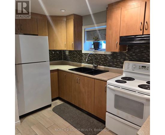 A kitchen with a white fridge, white stove, and wooden cabinets.