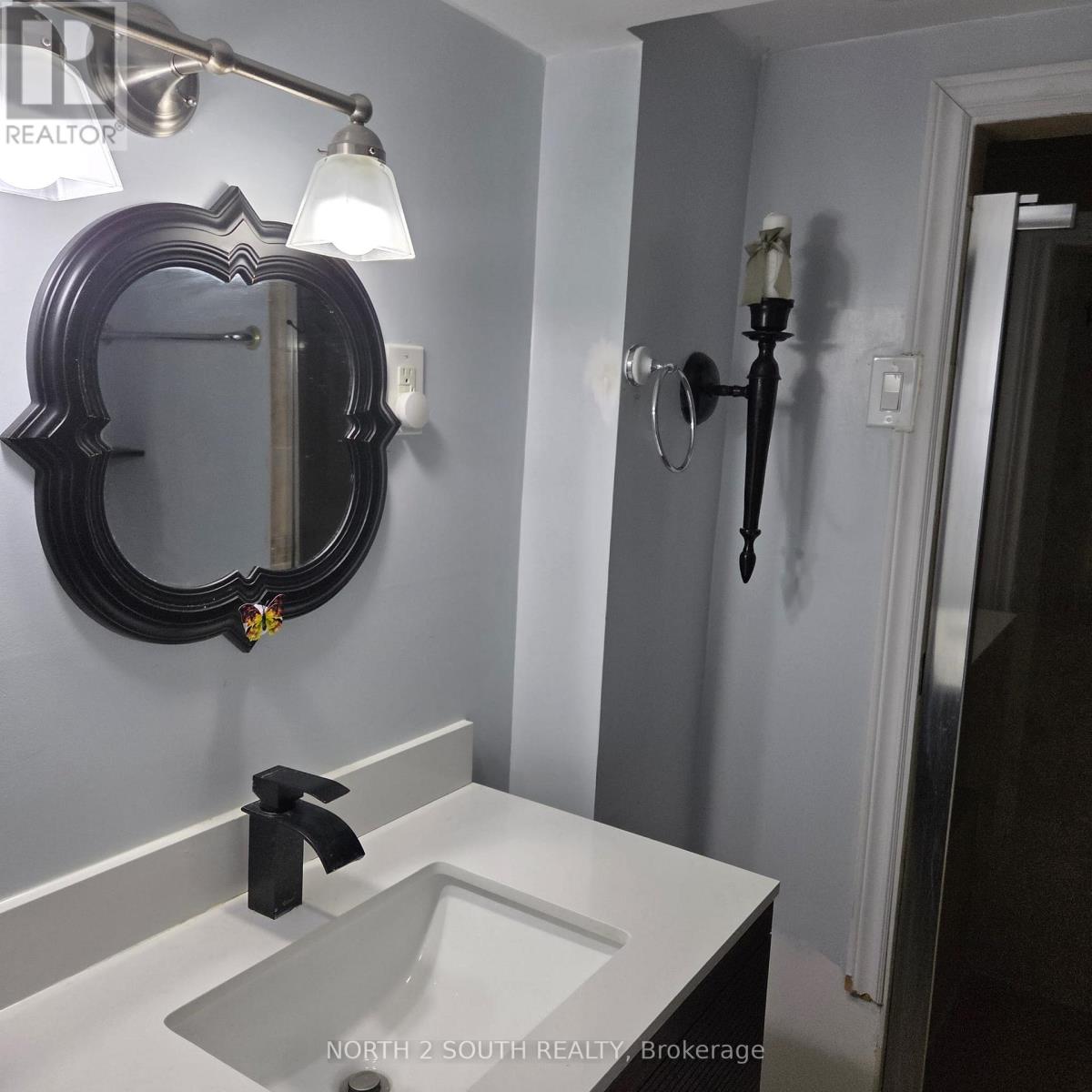 A bathroom with a sink, mirror and light fixture.