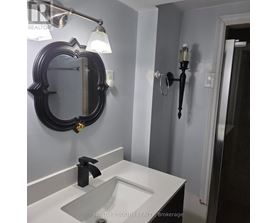 A bathroom with a sink, mirror and light fixture.