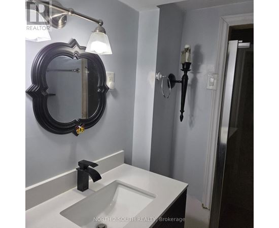 A bathroom with a sink, mirror and light fixture.