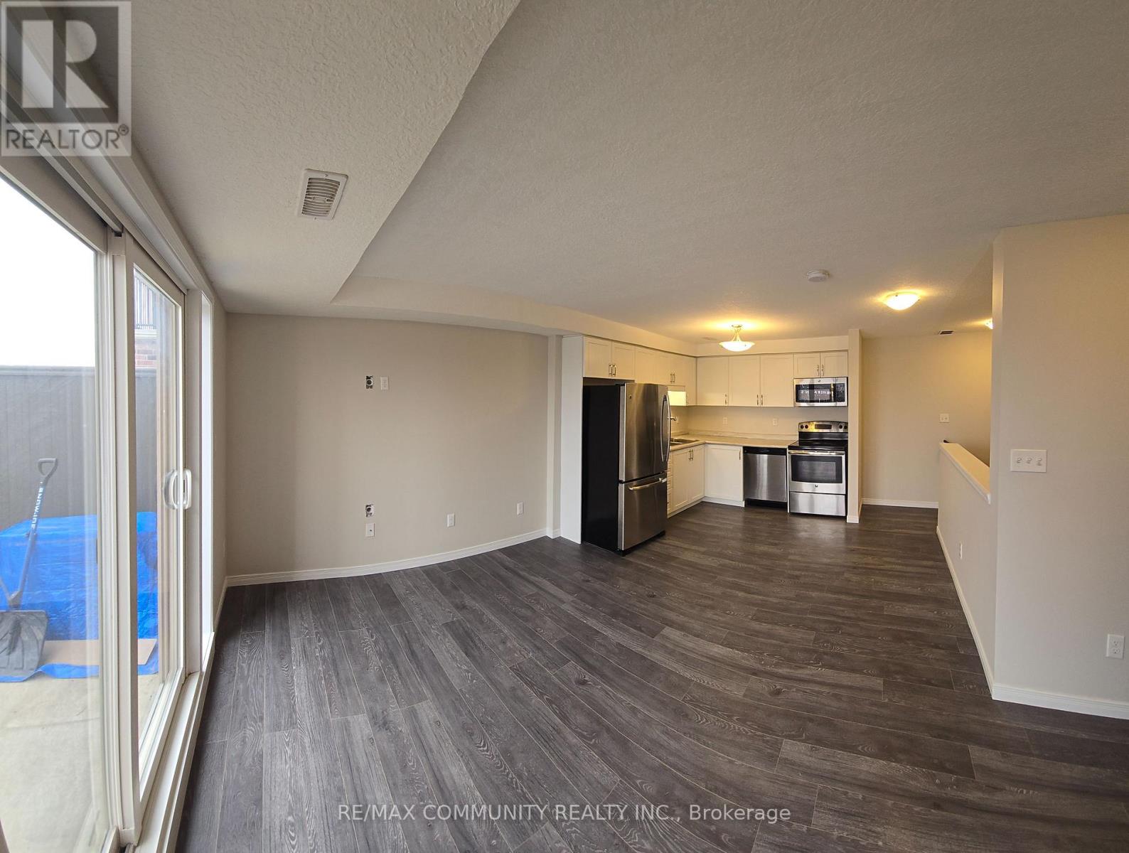 A spacious room with a kitchenette and a view of a pool through a glass door.