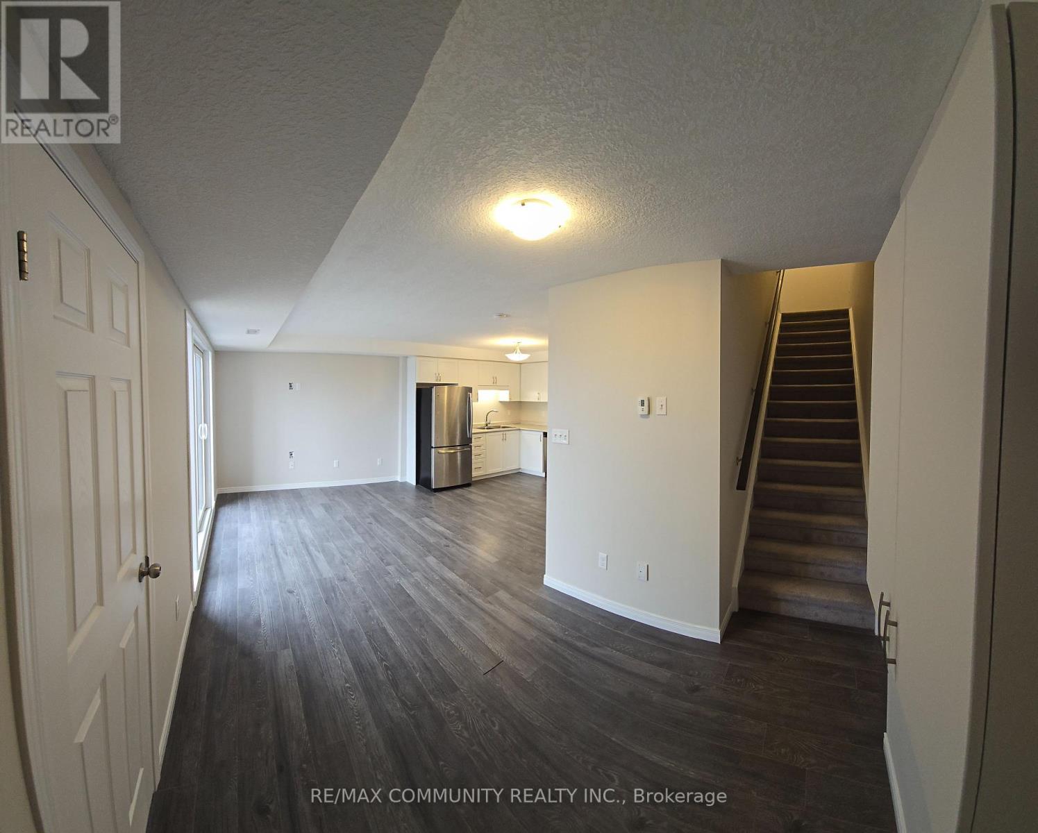 A spacious room with wooden flooring and a staircase leading to another level.
