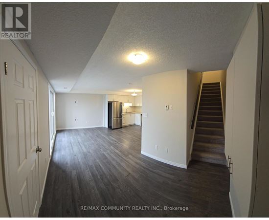 A spacious room with wooden flooring and a staircase leading to another level.