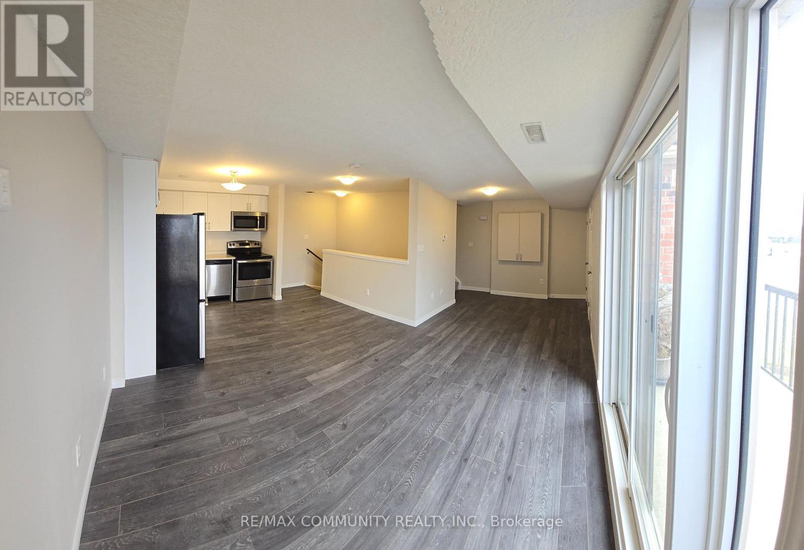 A spacious room with wood flooring and a large window.
