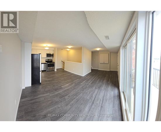 A spacious room with wood flooring and a large window.