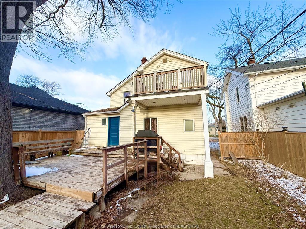 A house with a deck and a tree in front.