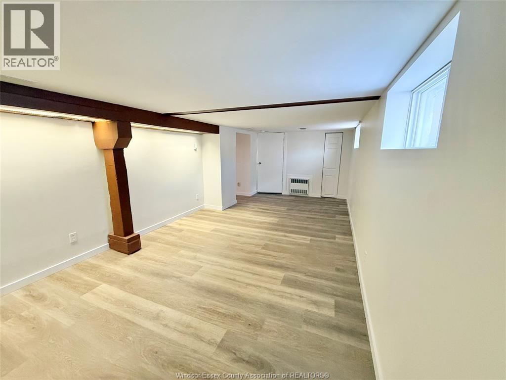 A spacious room with wooden flooring and a large window.