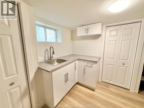 A small white kitchen with a sink and a window.