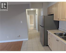 A kitchen with a refrigerator, sink, and cabinets.