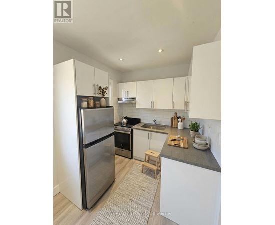 A modern kitchen with a stainless steel refrigerator and white cabinets.