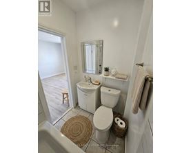 A white bathroom with a toilet, sink, and mirror.
