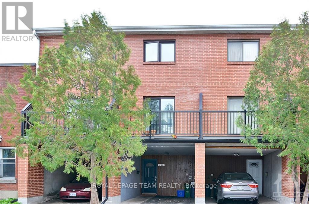A red brick building with a balcony and a car parked in the driveway.