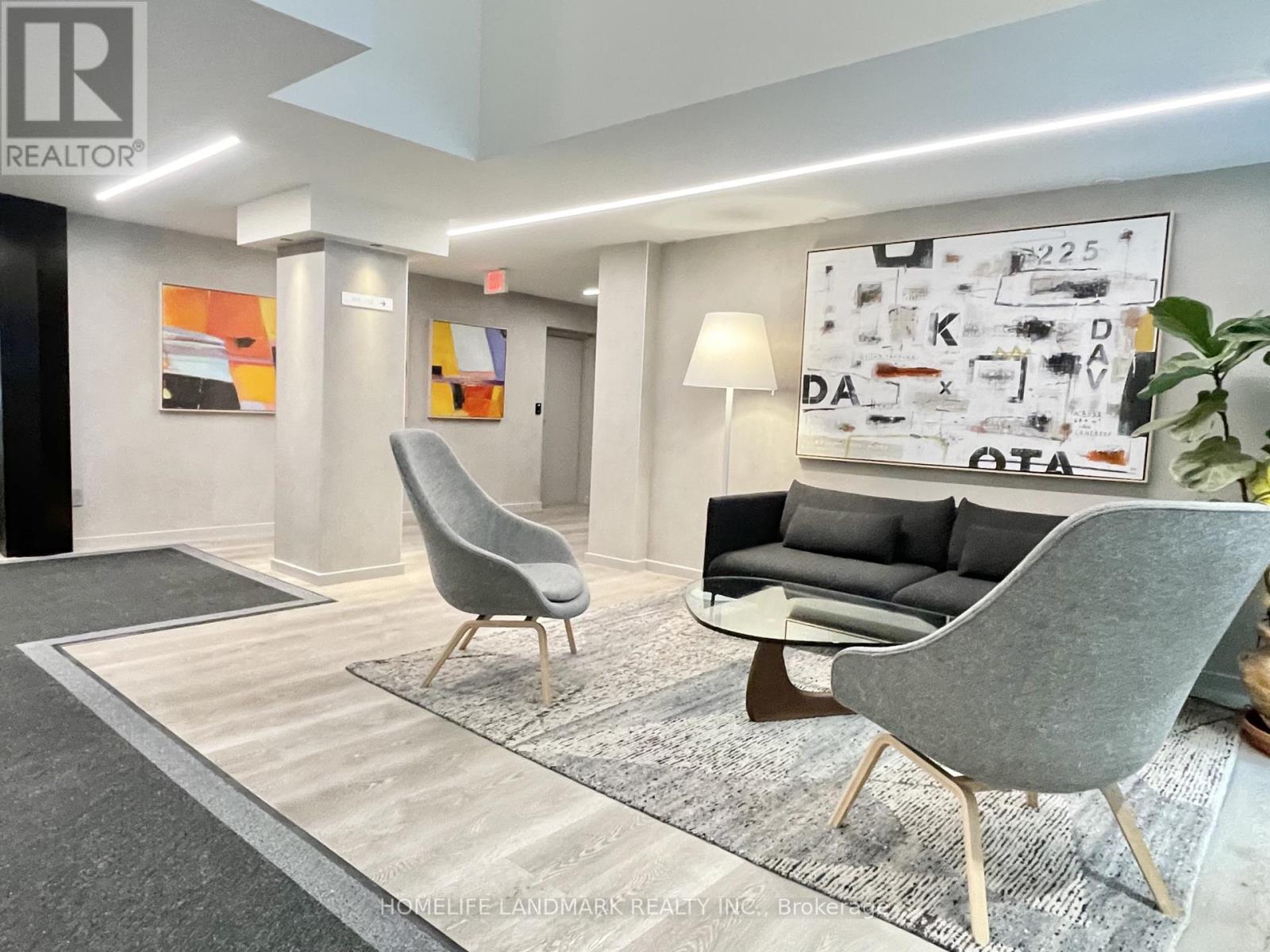 A modern living room with a grey sofa, two grey chairs, and a rug.