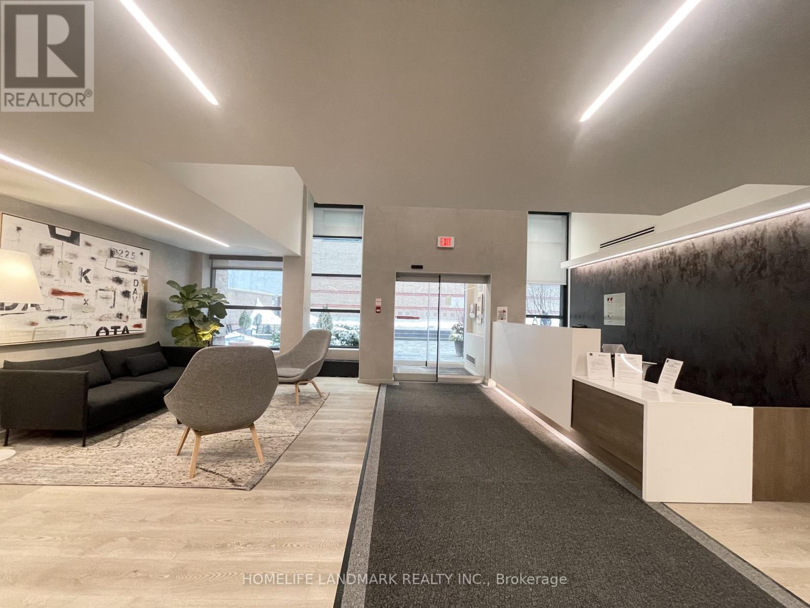 A modern office lobby with a reception desk and a large window.