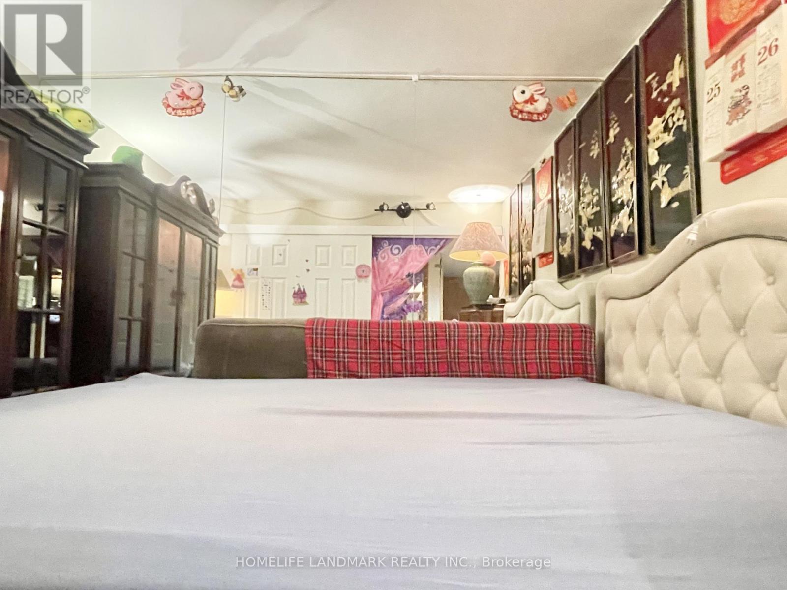 A bedroom with a bed, a couch, and a wall with pictures.