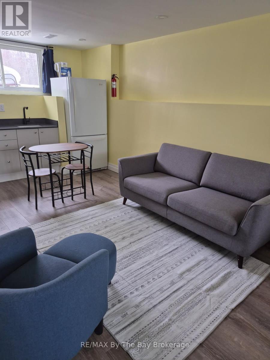 A grey couch sits in a living room with a round table and a blue chair.